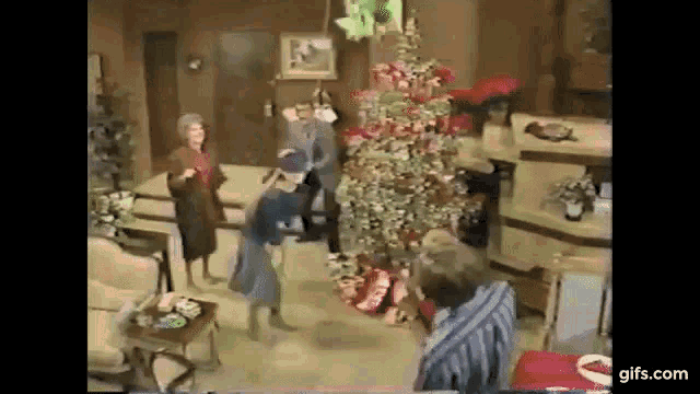 a group of people are dancing around a christmas tree .