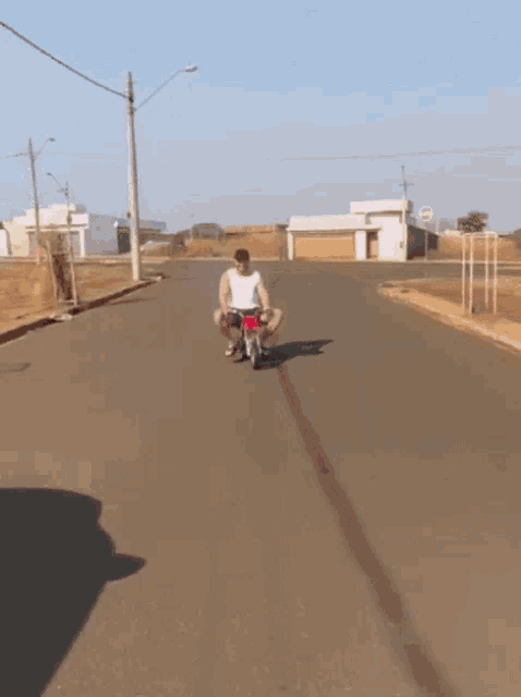 a man is squatting on a red motorcycle on a road