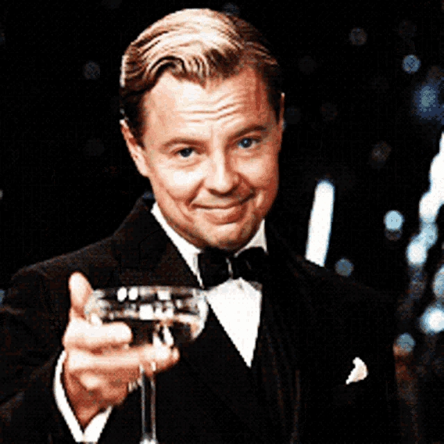 a man in a tuxedo is holding up a glass of wine