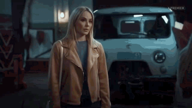a woman in a brown jacket is standing in front of a white van .