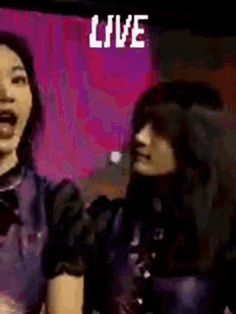 a couple of women are standing next to each other in front of a live screen .