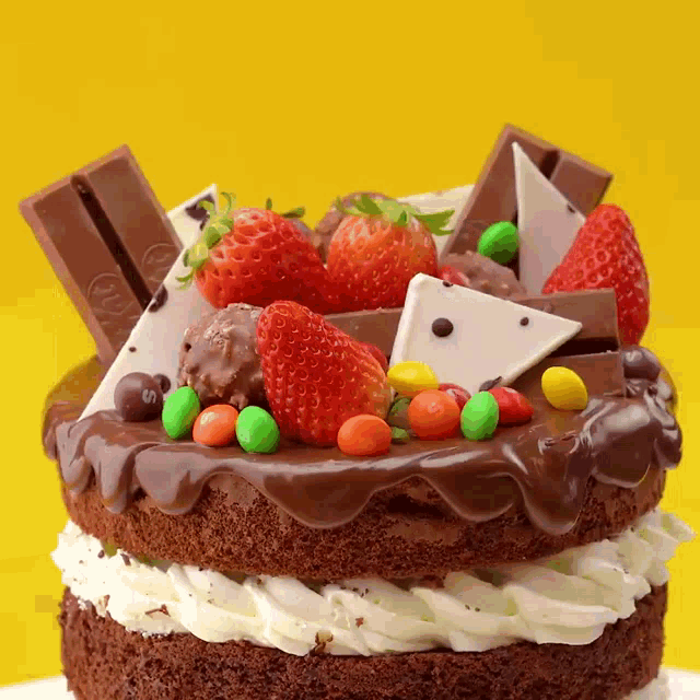 a chocolate cake with whipped cream and strawberries and kitkat bars on top