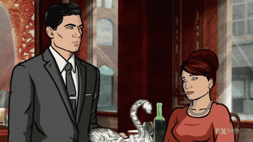 a man in a suit and tie stands next to a woman in a red top