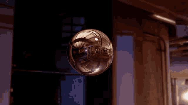 a glass ball with a reflection of a building is floating in the air