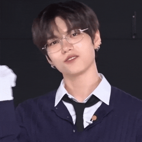 a young man wearing glasses and a tie is giving a thumbs up sign .