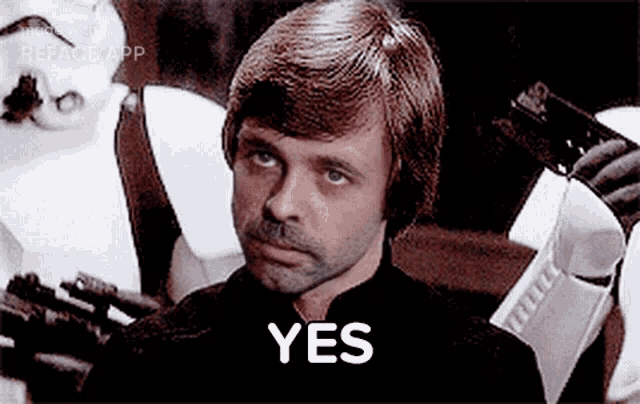 a man with a beard is sitting in front of a group of stormtroopers .
