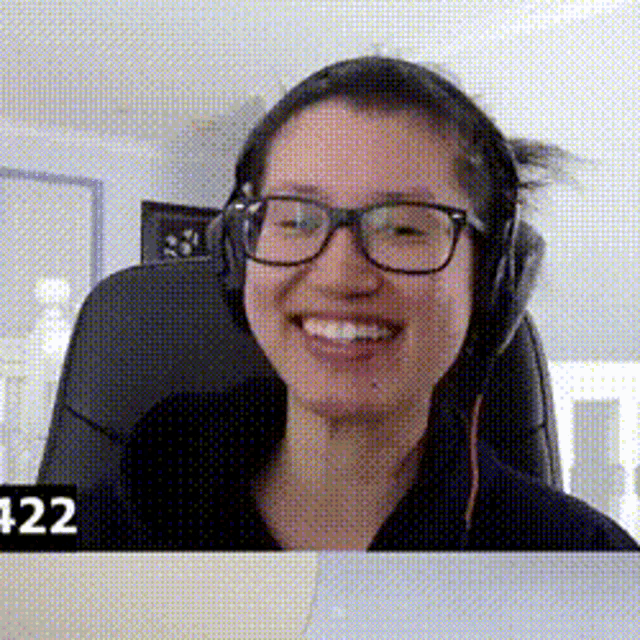 a woman wearing glasses and headphones is smiling and sitting in a chair .