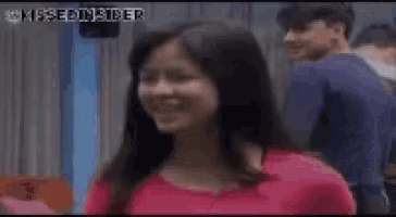 a woman in a pink shirt is smiling while standing next to a man in a blue shirt .