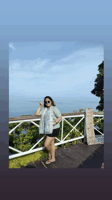 a woman is standing on a wooden deck overlooking the ocean