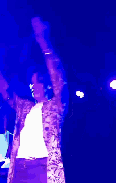 a person with their arms in the air in front of a microphone