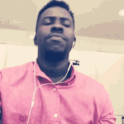 a man wearing headphones and a pink shirt with the letter b on the front