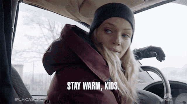 a woman in a car with the words stay warm kids on the screen