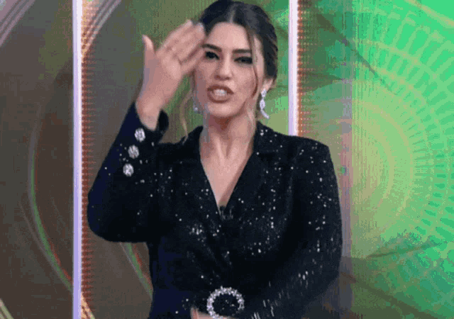 a woman in a black sequined jacket is giving a thumbs up sign