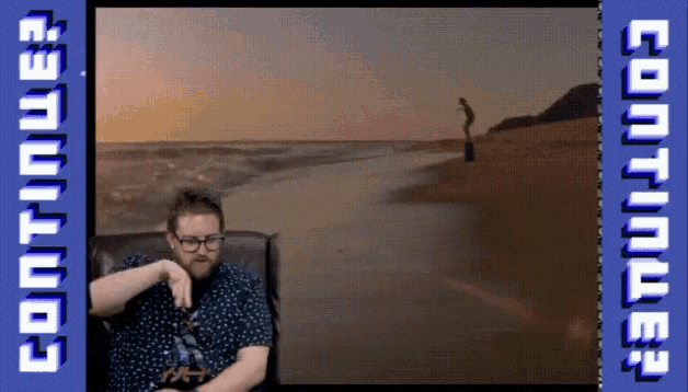 a man is sitting in front of a screen that says continue