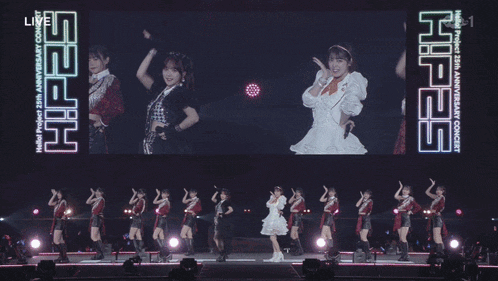 a group of girls are standing in front of a large screen that says hello project 25th anniversary concert on it