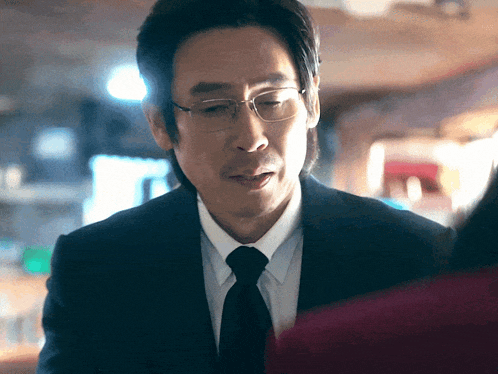 a man wearing glasses and a suit is looking at a woman