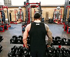 a man is lifting dumbbells in a gym .
