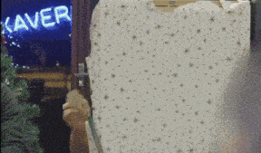 a person is holding a shirt in front of a kaver sign