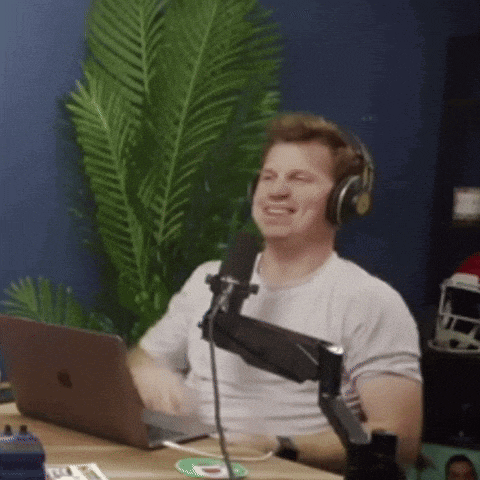 a man wearing headphones is sitting in front of a microphone with an apple laptop