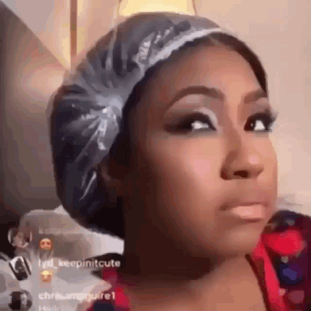 a woman wearing a plastic shower cap on her head is making a funny face .