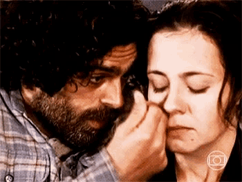 a man with a beard is touching a woman 's face with his hand .