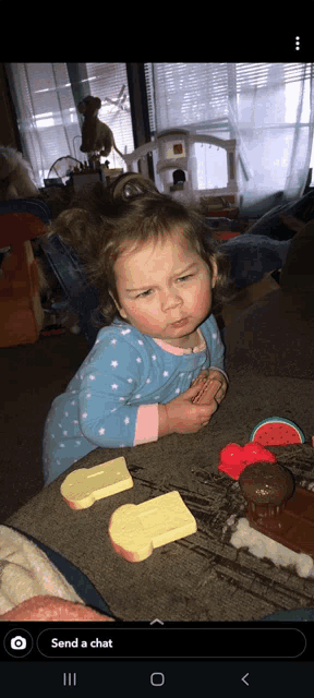 a little girl in a blue and pink pajama is playing with a toy train