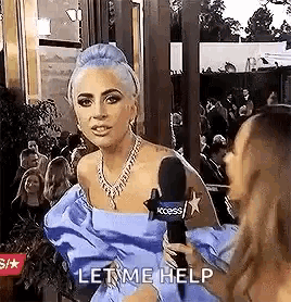 lady gaga is wearing a blue dress and holding a microphone while talking to a reporter on a red carpet .