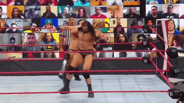 two men are wrestling in a wrestling ring in front of a crowd of people .