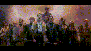 a group of people standing on a stage with a man holding a sword in the middle