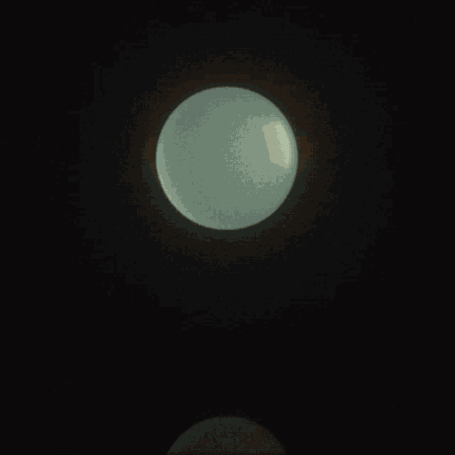 a light shines on a sphere that is floating in the dark