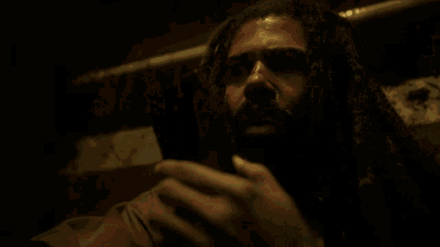 a man with long dreadlocks is holding a large knife in his mouth