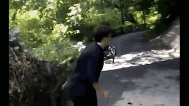 a man is walking down a road with trees on the side of it .
