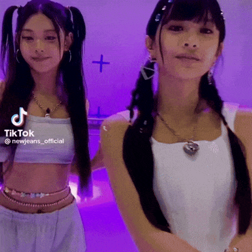 two girls are standing next to each other in front of a purple wall with a tiktok logo on the bottom