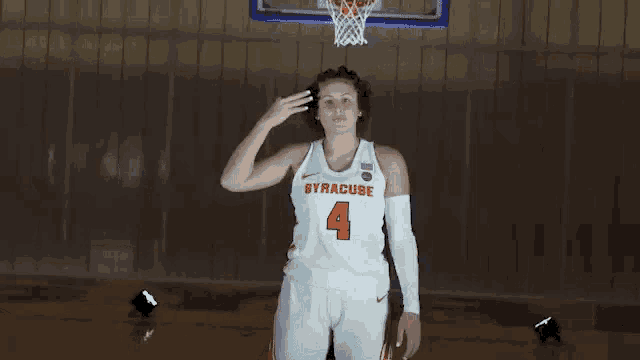 a woman in a syracuse basketball uniform is saluting while standing on a basketball court .