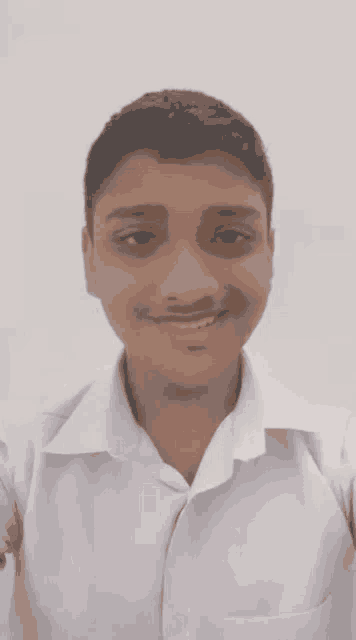 a young boy wearing a white shirt is smiling for the camera .