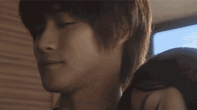 a close up of a man 's face with a woman behind him with her eyes closed