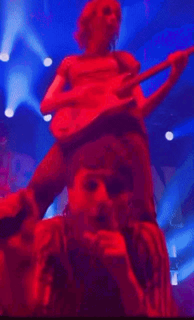 a man is singing into a microphone while another man plays a guitar on stage