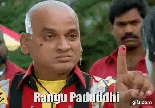 a bald man with a red ink stain on his finger is giving a thumbs up .