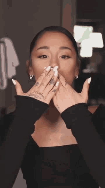 a woman with a tattoo on her finger that says ' ariana grande ' on it