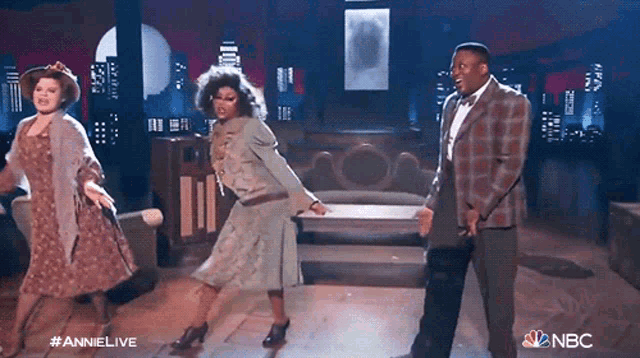 a group of people are dancing on a stage with the nbc logo behind them