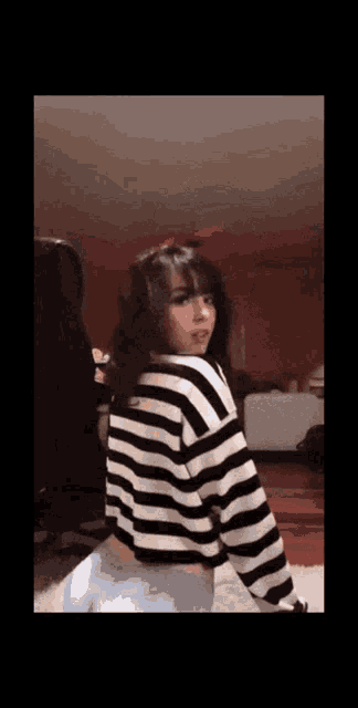 a woman in a black and white striped sweater is dancing