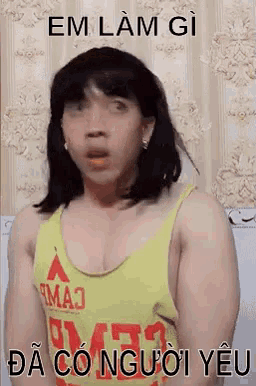a man in a yellow tank top is making a funny face while wearing a wig .