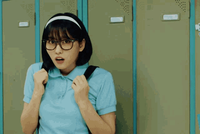 a young girl wearing glasses and a headband is standing in front of lockers .