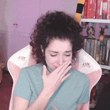 a woman sits in a pink and white dx chair covering her mouth