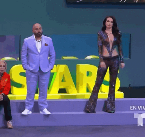 a man in a suit stands next to a woman in a very revealing outfit in front of a sign that says star