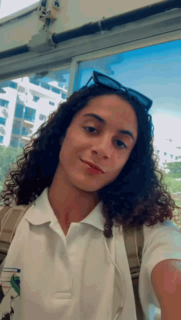 a woman with long curly hair is taking a selfie