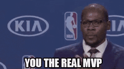 a man in a suit and tie is standing in front of a kia logo and applauding .