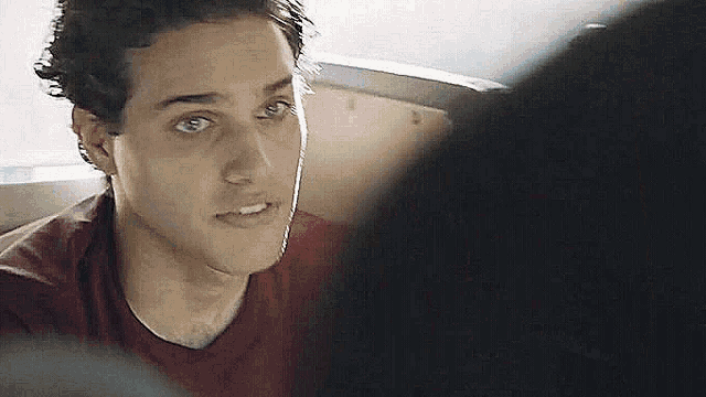 a close up of a man 's face in a red shirt looking at the camera .