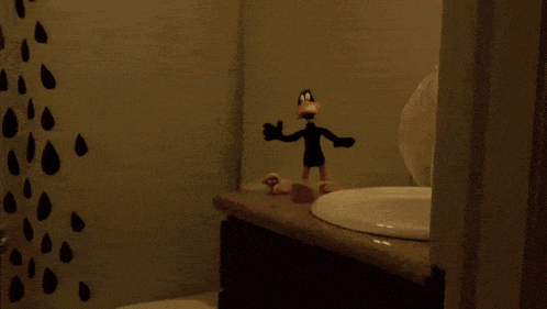 a bathroom with a toilet sink and a duck figurine
