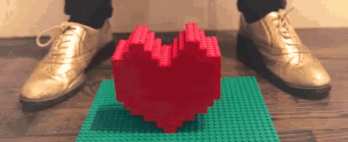 a person in gold shoes is standing next to a lego heart